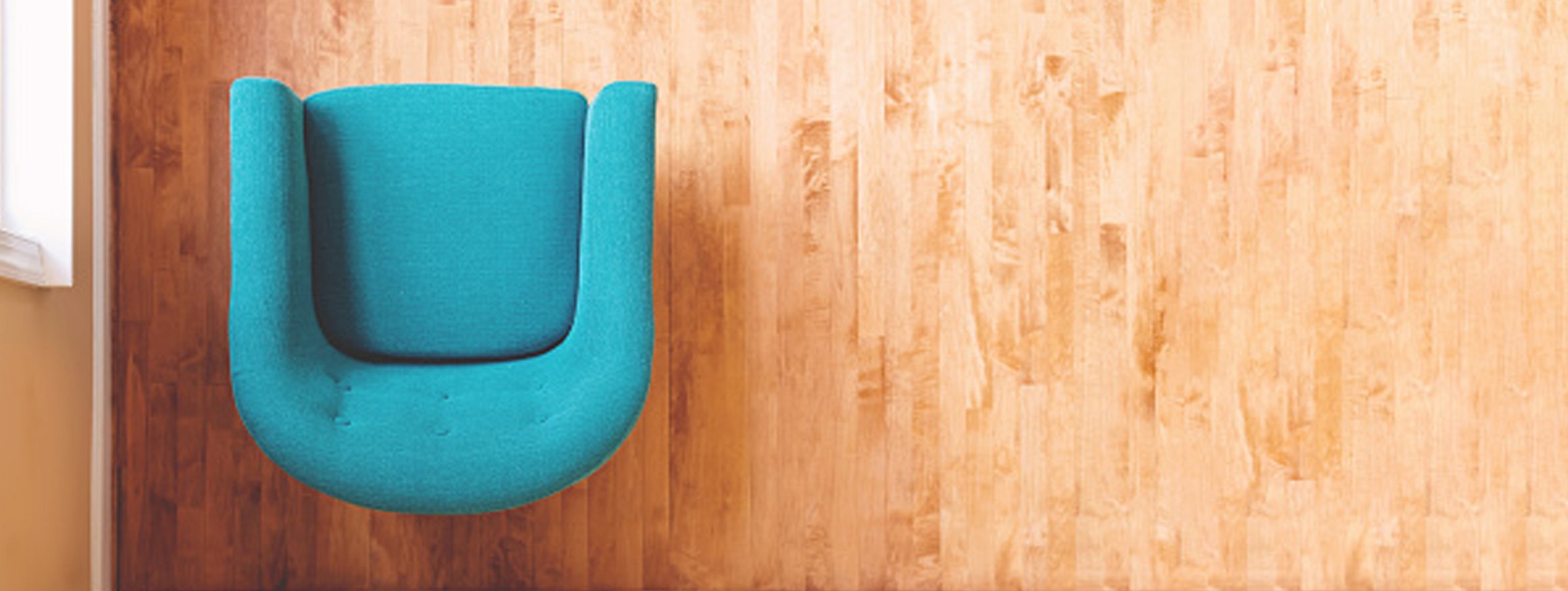 Ein blauer Sessel steht in einem hellen Raum mit hellen Holzboden in dem eine Psychotherapie stattfindet