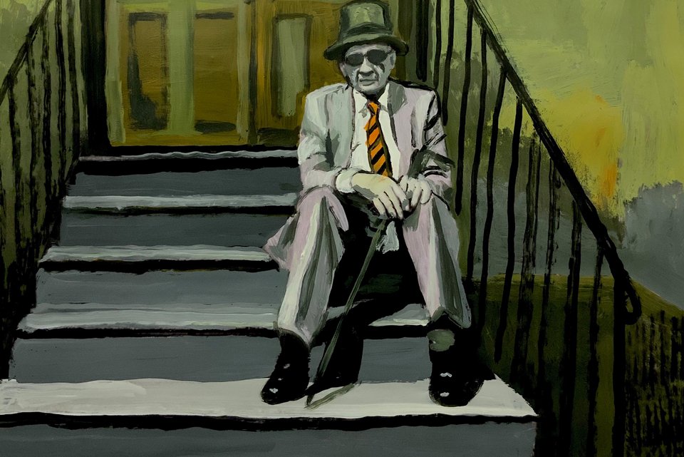 Ein älterer Mann sitzt im Anzug, Hut und Sonnenbrille auf einer Treppe vor einem Hauseingang und hält dabei einen geschlossenen Regenschirm zwischen seinen Beinen