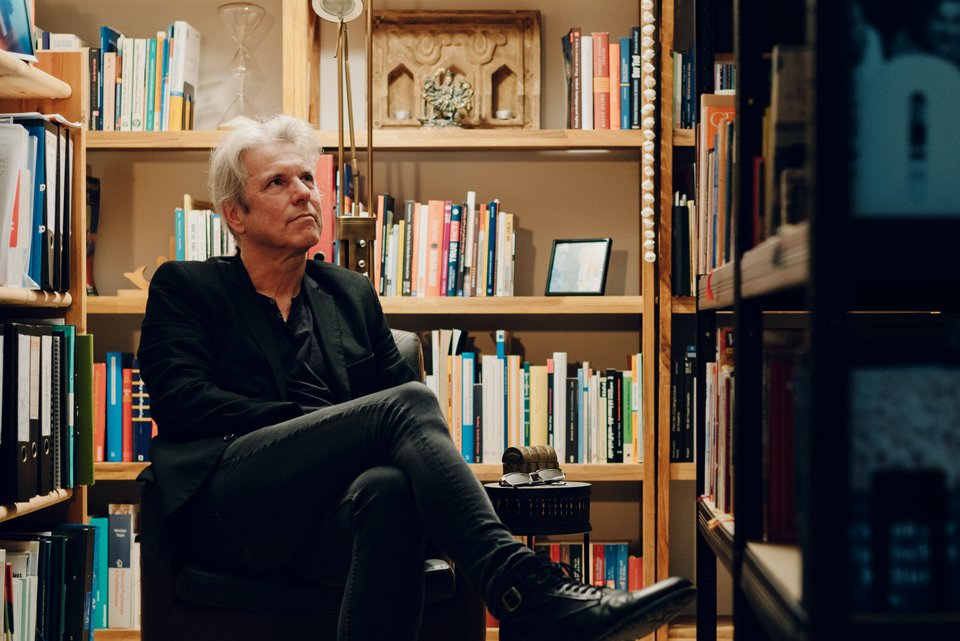 Der Psychoanalytiker und Verhaltenstherapeut, Ralf T. Vogel, sitzt in einem Sessel vor Bücherregalen