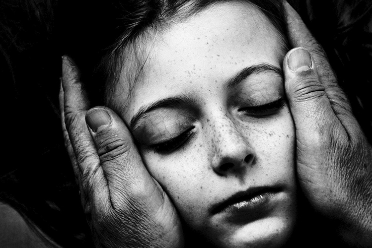 Das Foto zeigt zwei Hände, die tröstend das Gesicht eines Kindes halten
