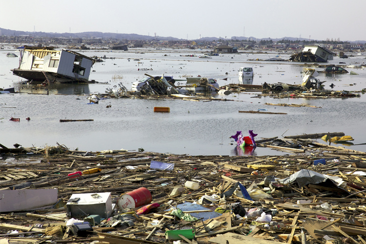 Das Foto zeigt eine verwüstete und überflutete Landschaft in Fukushima 2011 als Beispiel für die vermutete Rache der Natur