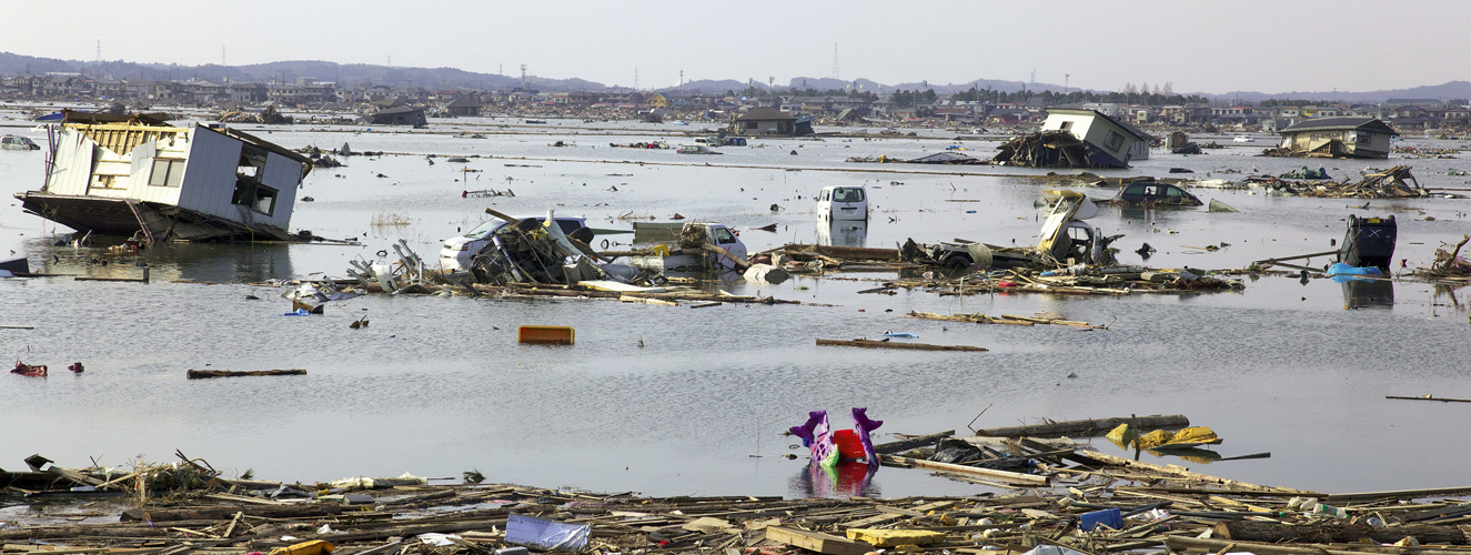 Das Foto zeigt eine verwüstete und überflutete Landschaft in Fukushima 2011 als Beispiel für die vermutete Rache der Natur