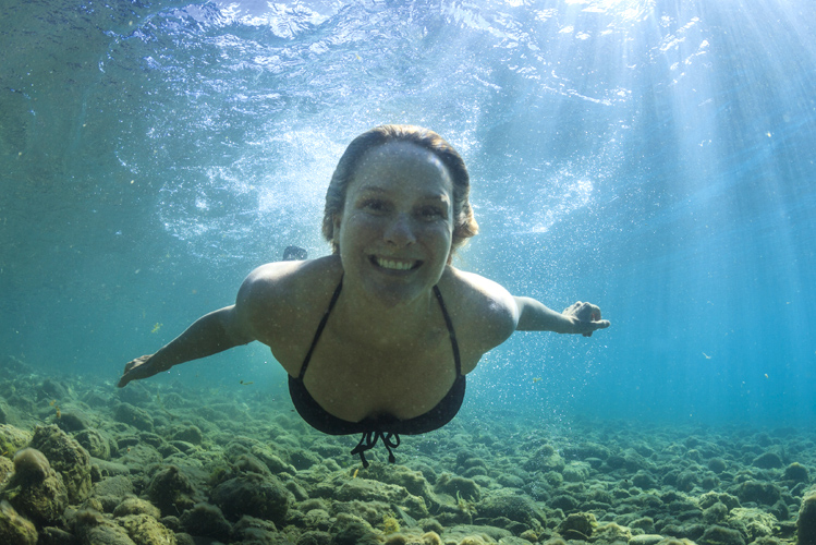 Eine Frau taucht lächelnd und genießt die besondere Wirkung von Wasser