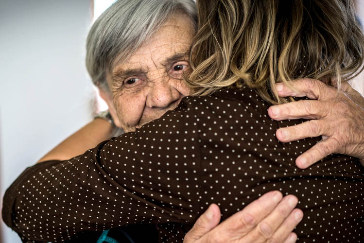 Eine Frau umarmt ihre ältere Mutter