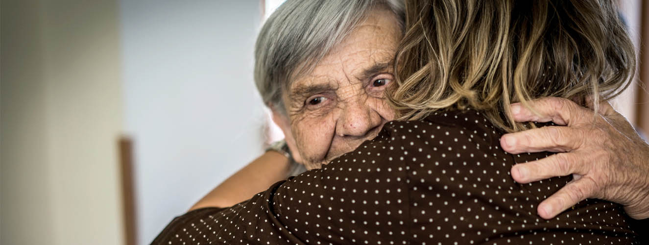 Eine Frau umarmt ihre ältere Mutter