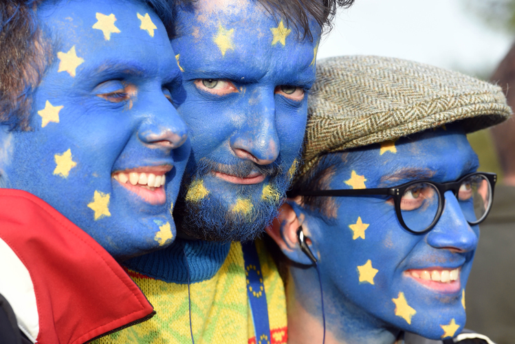 Foto zeigt drei Männer, die sich die Europafahne ins Gesicht gemalt haben. 