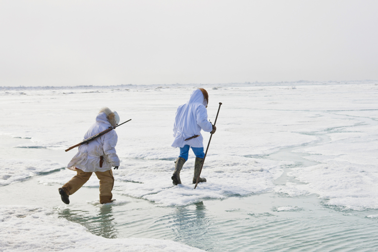 Zwei Inuits in Alaska laufen mit Jagdausrüstung über das Eis und gehen einer alten Tradition nach, die für sie physisch und psychisch wichtig ist
