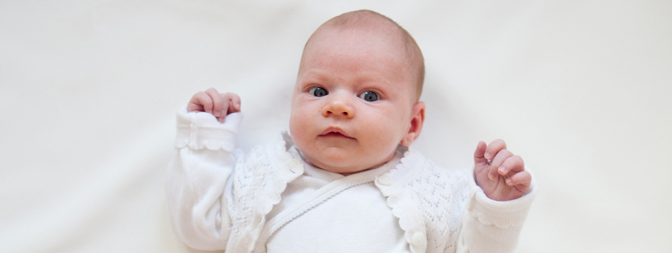 Ein Baby, das aus einer Babyklappe gerettet wurde, liegt gut angezogen und zufrieden da