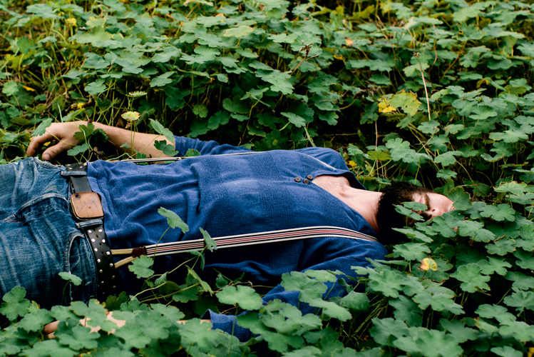 Foto zeigt einen jungen Mann, der entspannt in der grünen Natur liegt 