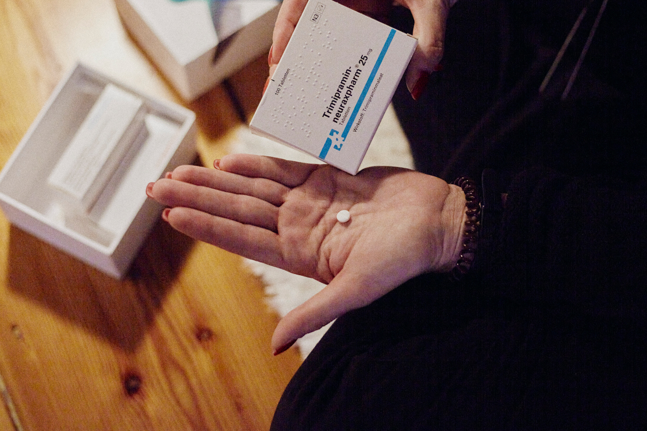 Eine Frau hält in der linken Hand eine weiße Tablette und in der rechten Hand die Verpackung