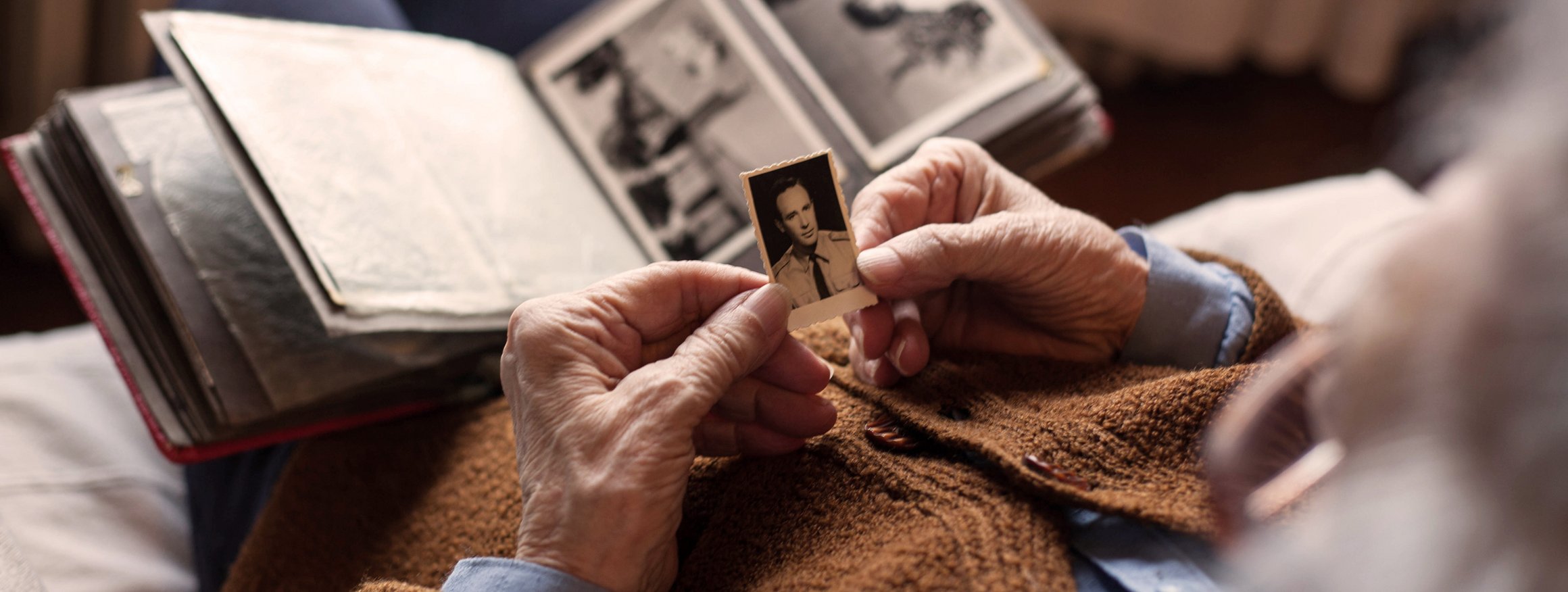 Eine alte Frau hält ein altes schwarz-weiß Foto in der Hand und denkt an einen toten geliebten Menschen 