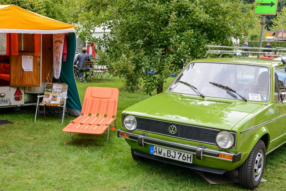 Ein grüner 1-er VW Golf steht auf einem nostalgischen Campingplatz