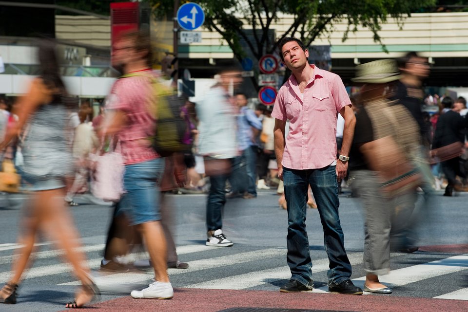 Foto zeigt einen Mann auf einem Zebrastreifen, der sich in negativen Gedanken verliert. 