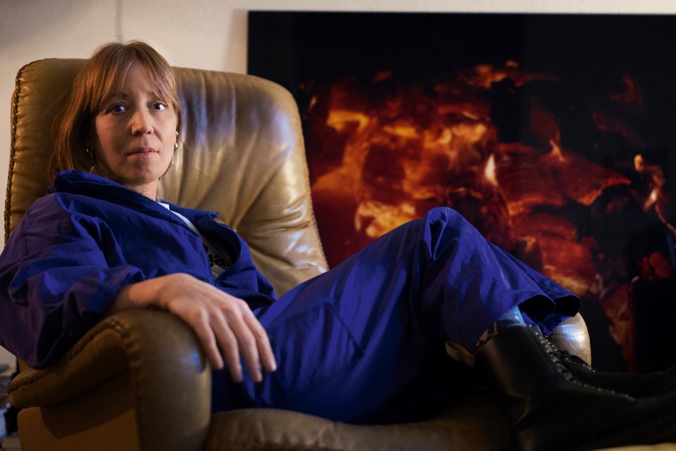 Die Journalistin Marlene Hasler sitzt in einem blauen Overall entspannt auf einem Sessel