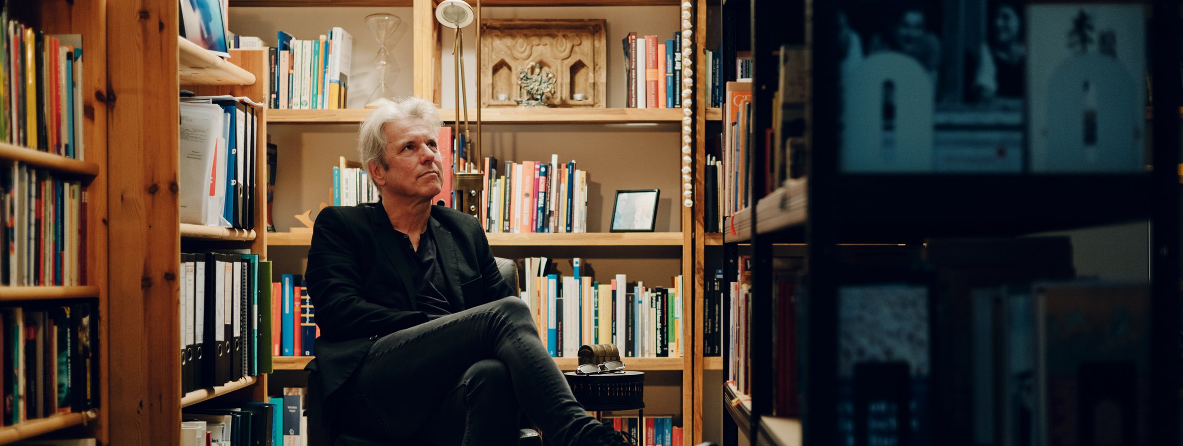 Der Psychoanalytiker und Verhaltenstherapeut, Ralf T. Vogel, sitzt in einem Sessel vor Bücherregalen