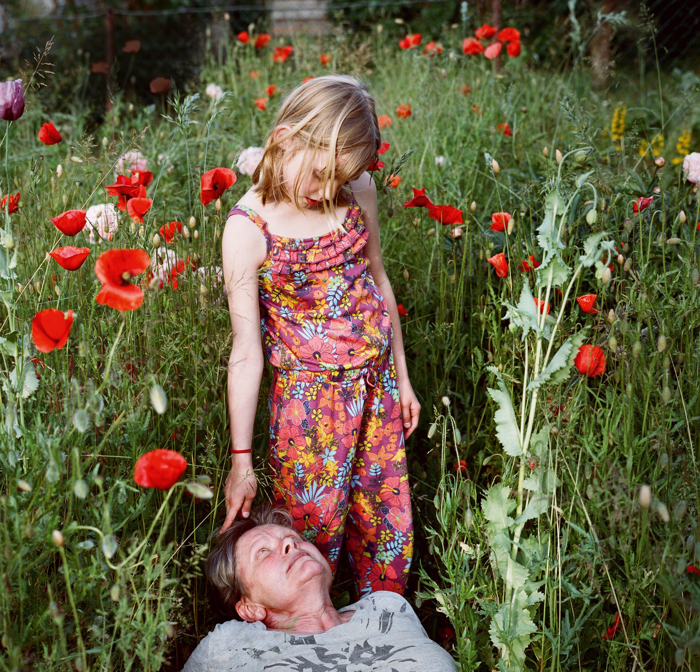 Das Foto zeigt eine ältere Frau, die im Gras liegt und ihre Enkelin.
