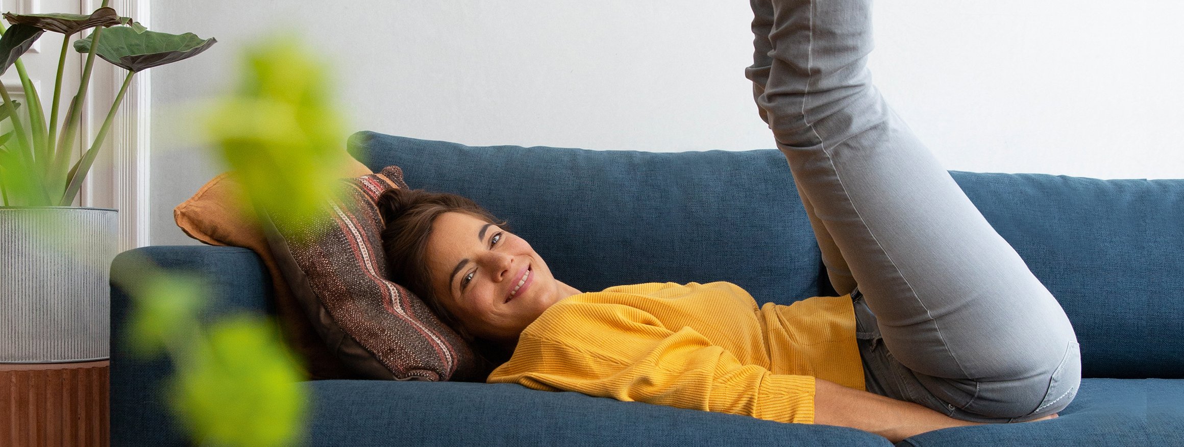 Foto zeigt eine Frau auf ihrem Sofa, die sich in ihrer Wohnung wohlfühlt. 