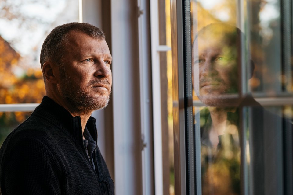 Der Schriftsteller Andreas Maier steht am Fenster und schaut auf das Hochhaus in der Nachbarschaft, aus dem er die Klimaanlage hören kann