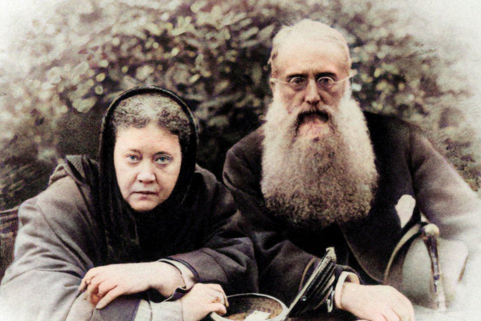 Die russische Okkultistin Helena Blavatsky sitzt im Garten zusammen mit ihrem engen Freund, Henry Steel Olcott, mit ernstem und fixierendem Blick
