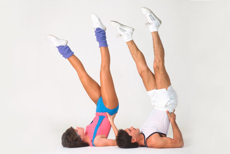 Ein Mann und eine Frau im 80er-Jahre-Look machen Aerobic