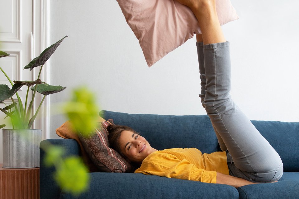 Foto zeigt eine Frau auf ihrem Sofa, die sich in ihrer Wohnung wohlfühlt. 