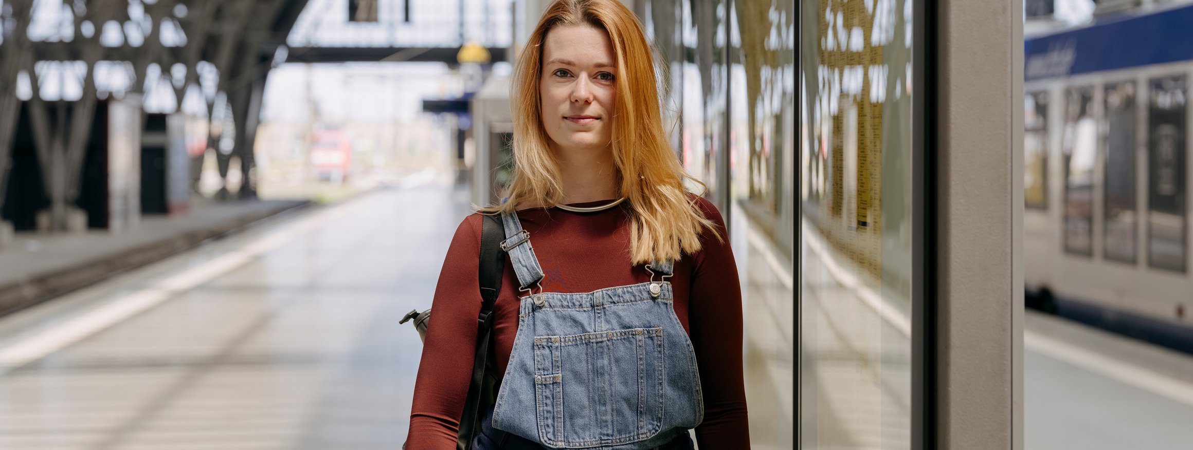 Christina Fetzer, die sich bei der European Dyslexia Association engagiert, steht mit Rucksack an einem Bahnhof und schaut entspannt, da sie keine Angst mehr vor Dyskalkulie hat