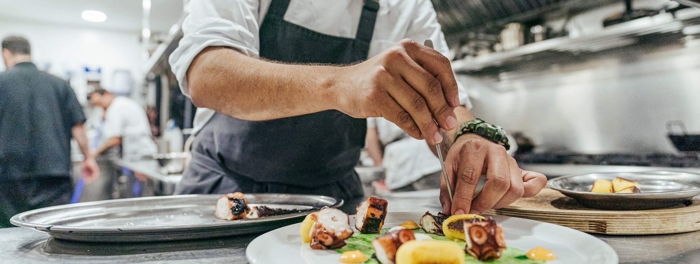 Ein Koch steht in einer Restaurantküche und bereitet einen Teller zu