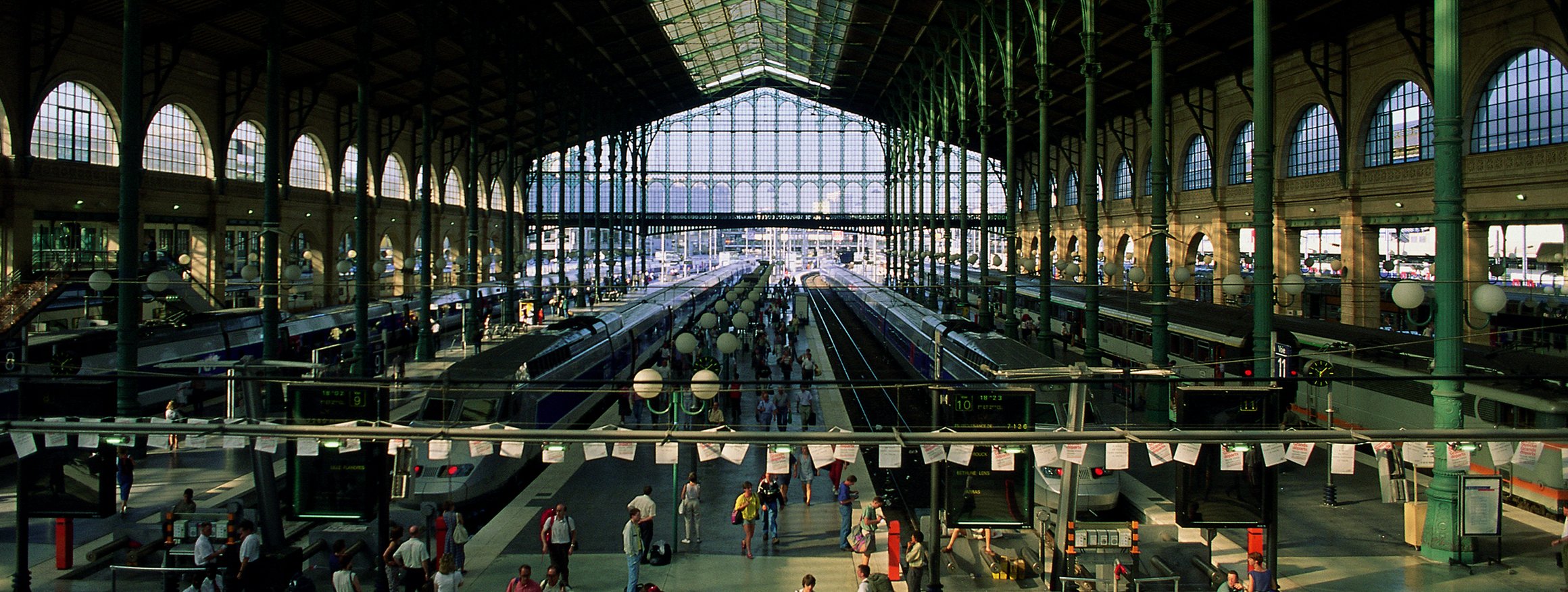 Eine große Bahnhofshalle mit Gleisen, Bahnsteigen und sehr vielen Menschen