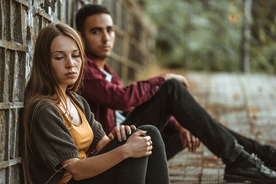Ein junges Paar sitzt traurig da und sie überlegt, ob sie noch mit ihm zusammen sein möchte