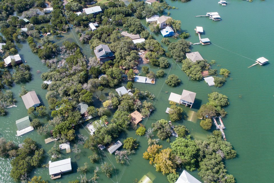 Eine Landschaft wurde von einem Fluss überflutet und man sieht von den Häusern größtenteils nur die Dächer aus dem Wasser ragen