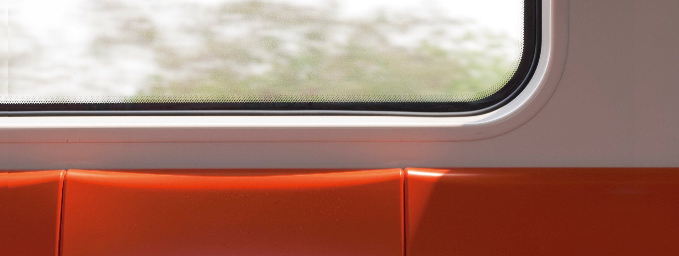 Eine rote Bank in einer S-Bahn mit Aussicht aus dem Fenster