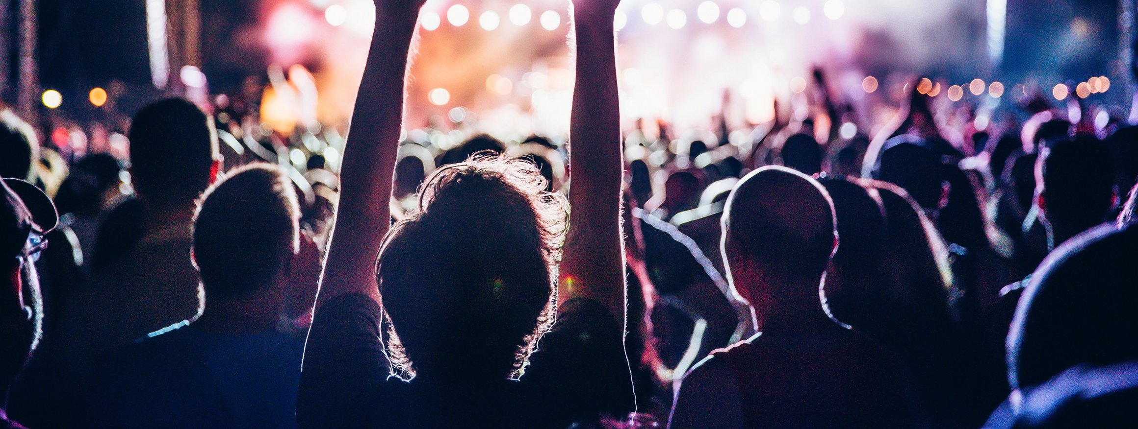 Viele Zuschauer auf einem Konzert, bei denen einige die Arme in die Höhe strecken