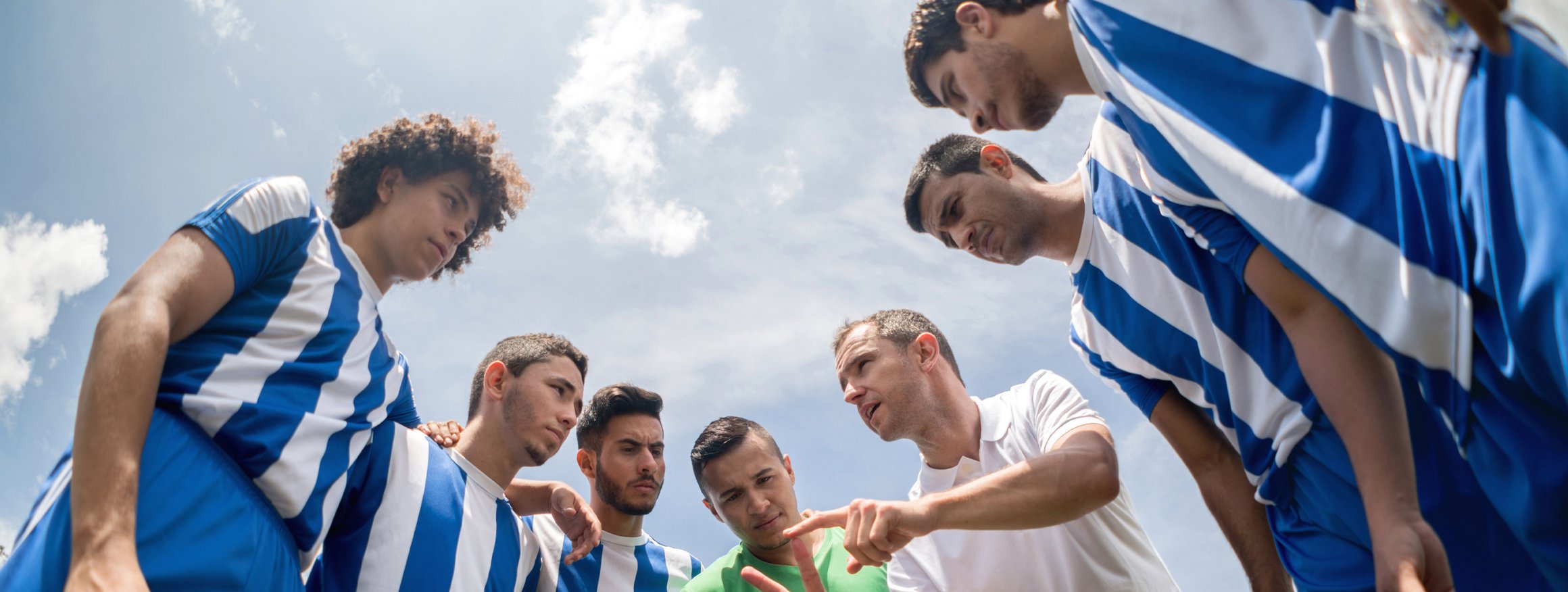 Ein Fußballtrainer steht da, umringt von seinem Team, und bespricht die Spieltaktik