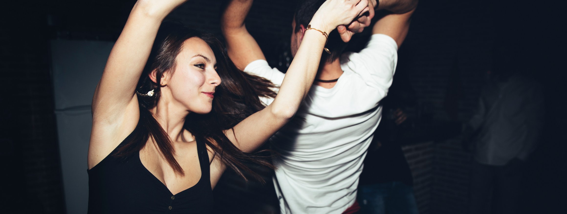 Ein junges Paar tanzt fröhlich in einem Club und kann ohne Worte ausdrücken, was es fühlt
