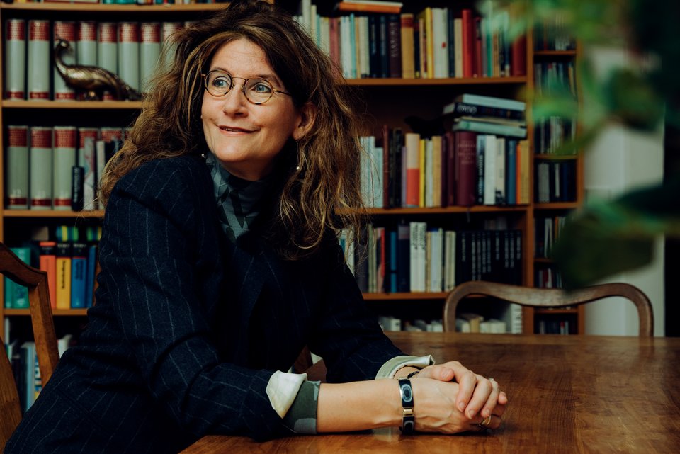 Die Autorin Anna Katharina Hahn sitzt an einem Holztisch, dahinter eine Bücherwand