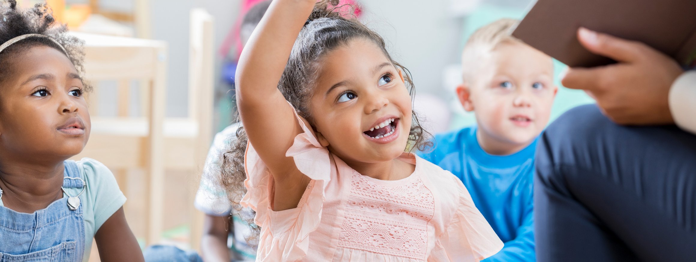 Grundschulkinder sitzen auf dem Boden mit ihrem Lehrer und haben Freude am Lernen