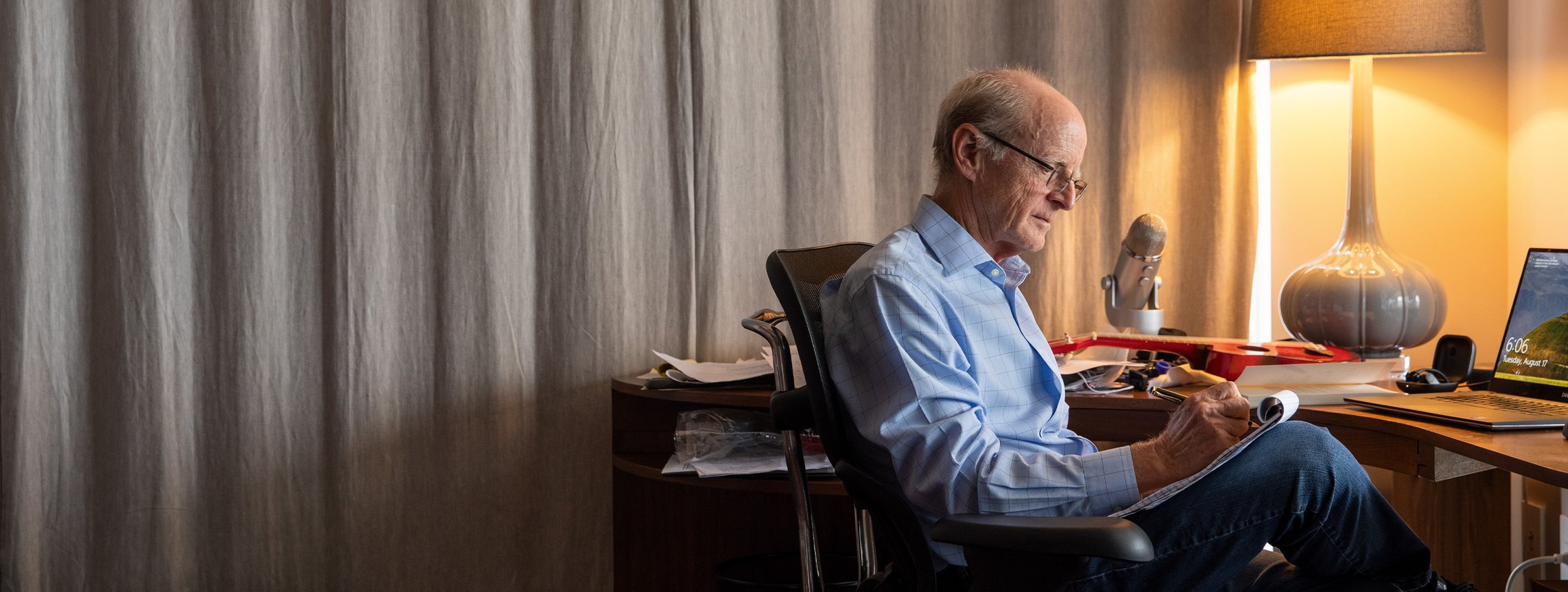 Der Professor und Psychologe, James Pennebaker, sitzt an seinem Schreibtisch und macht Notizen, daneben steht eine Lampe