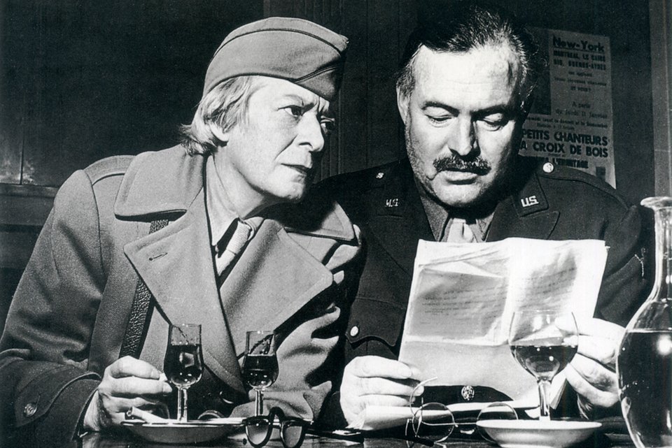 Die Schriftstellerin Janet Flanner und der Schriftsteller Ernest Hemingway sitzen in Paris gemeinsam am Tisch bei einem Glas Wein während des 2. Weltkriegs