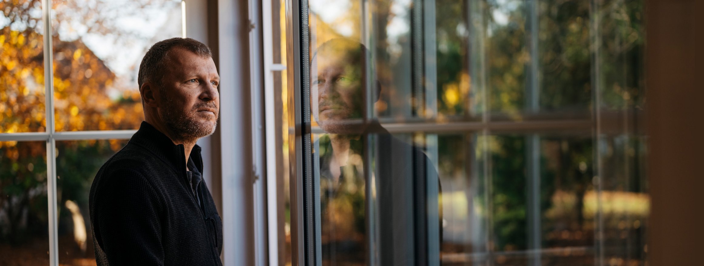 Der Schriftsteller Andreas Maier steht am Fenster und schaut auf das Hochhaus in der Nachbarschaft, aus dem er die Klimaanlage hören kann