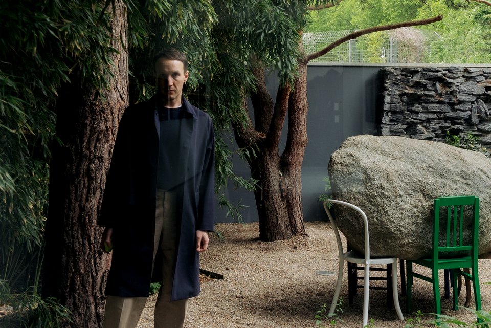 Der Schriftsteller Timon Karl Kaleyta steht im Garten der Pace Gallery/Galerie Judin in Berlin neben einem Kunstobjekt der Künstlerin Alicja Kwade
