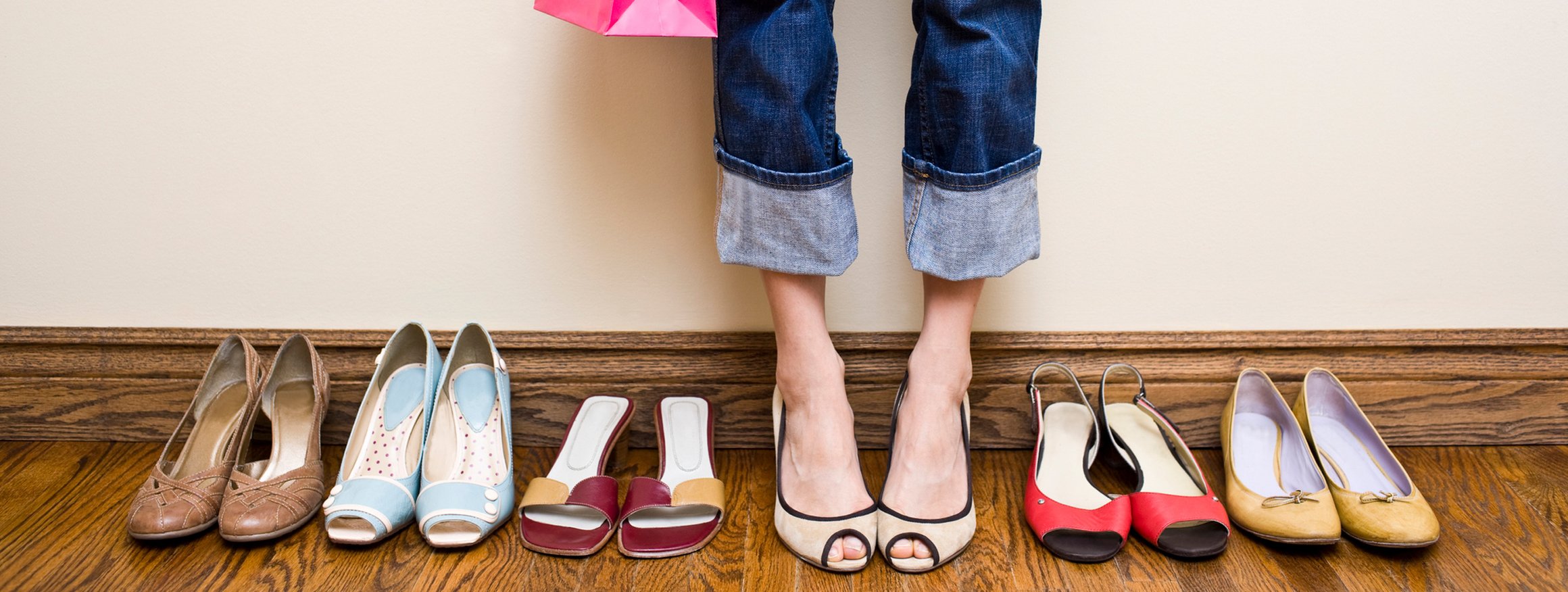 Eine Frau steht mit ihrer Einkaufstüte bei ihren vielen Schuh und konsumiert immer mehr