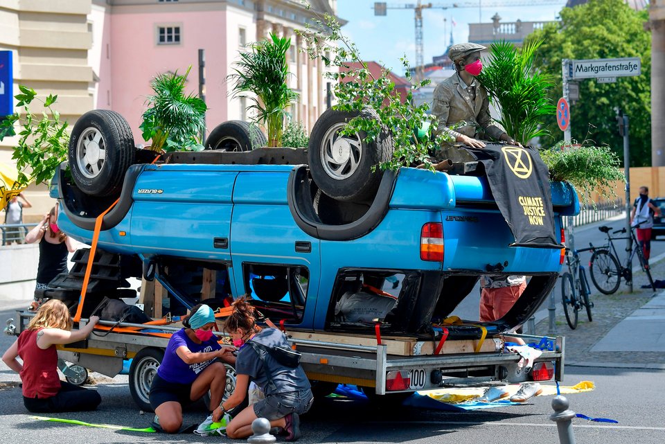 In Berlin demonstrieren im Juni 2020 Klimaaktivisten der Extinction-Rebellion-Bewegung mitten auf der Straße mit einem blauen Auto, das auf dem Kopf steht