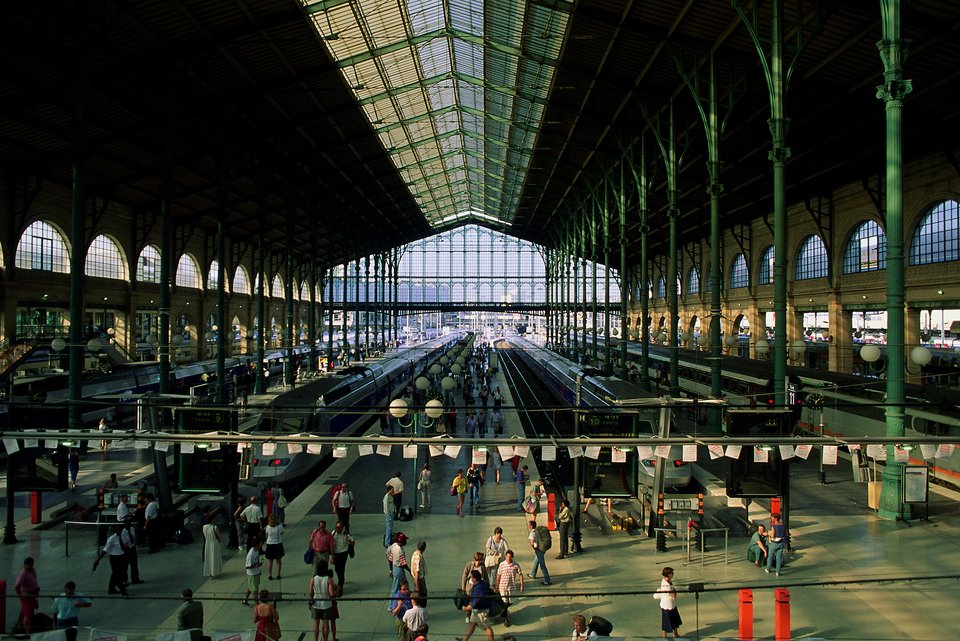 Eine große Bahnhofshalle mit Gleisen, Bahnsteigen und sehr vielen Menschen