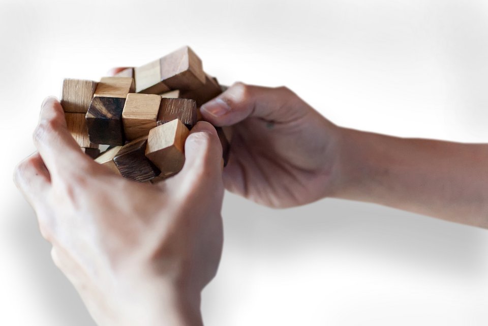 Zwei Hände halten einen Holzzauberwürfel und lösen das Spiel auf schnelle Weise