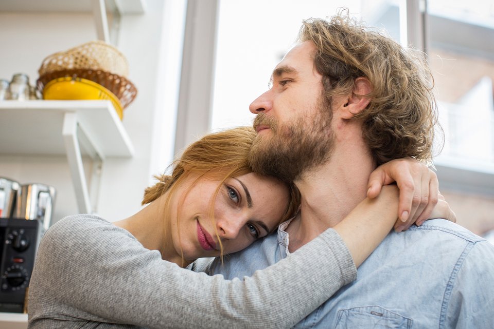 Foto zeigt ein junges Paar in seiner Wohnung, das sich umarmt