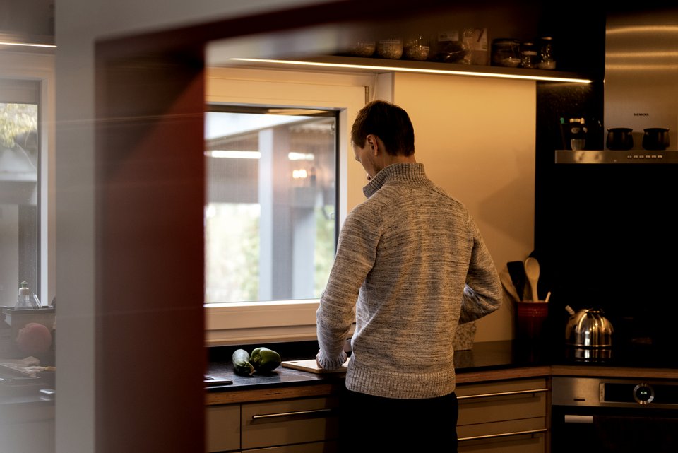 Ein sehr schlanker Mann steht in der Küche und bereitet sich ein Essen vor