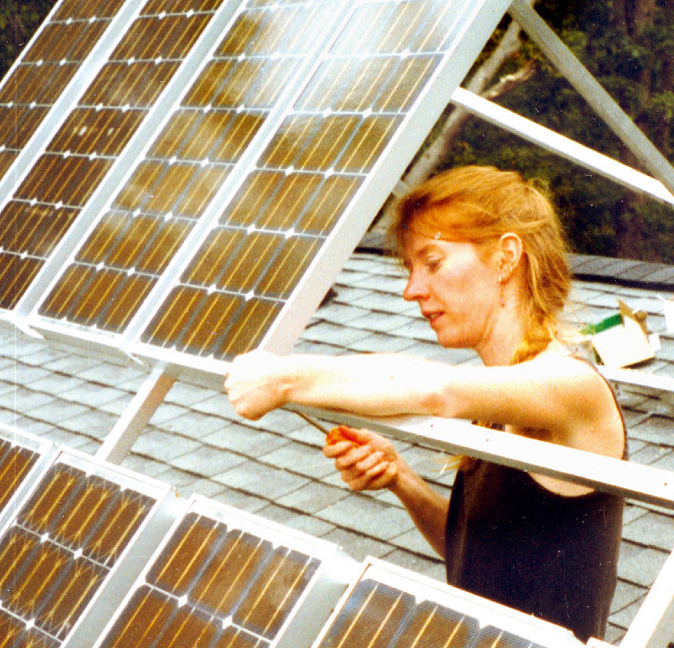Das Bild zeigt eine Frau, die an Solarpanelen schraubt.