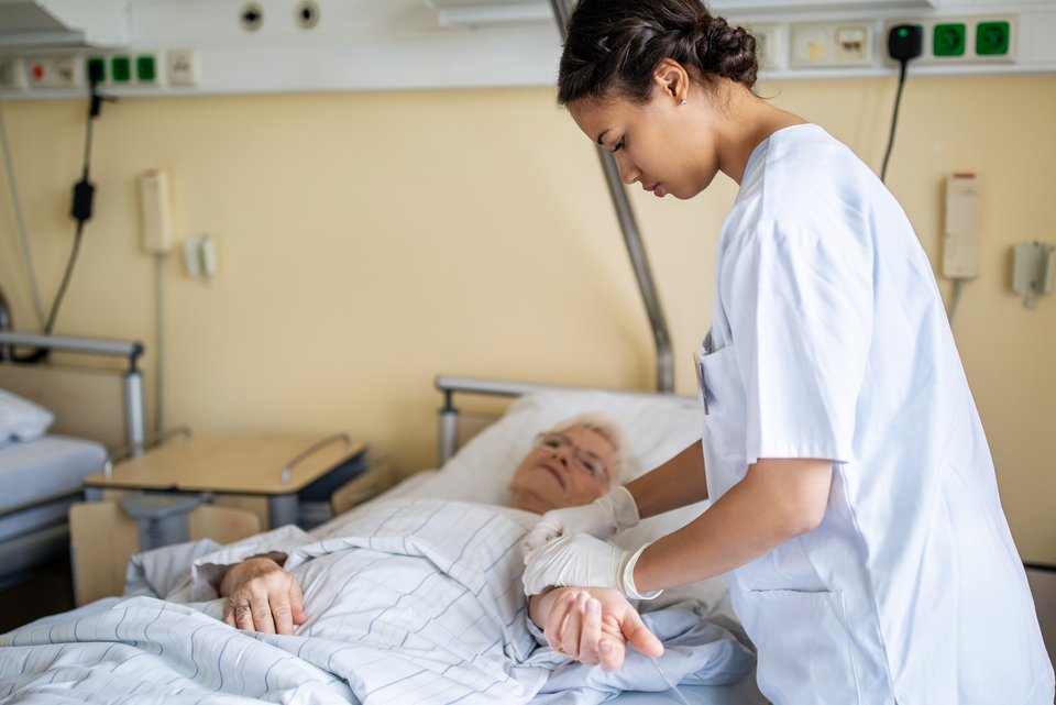 Eine Krankenschwester im Krankenhaus behandelt eine ältere Frau im Krankenbett