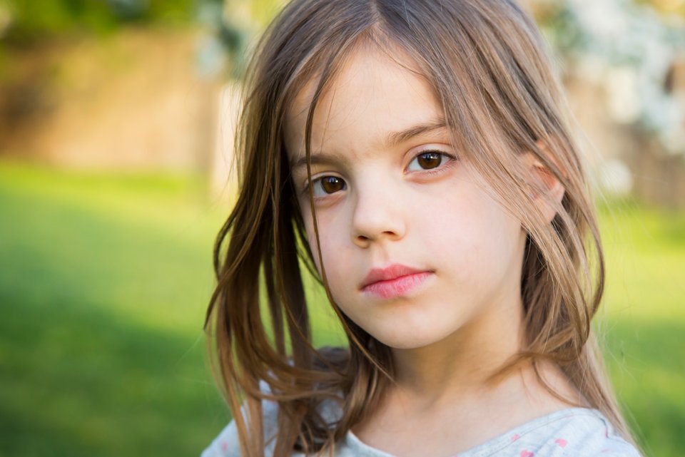 Ein Mädchen schaut ist schweigsam im Kindergarten und schaut dabei nachdenklich, während sie zuhause munter drauflosplappert