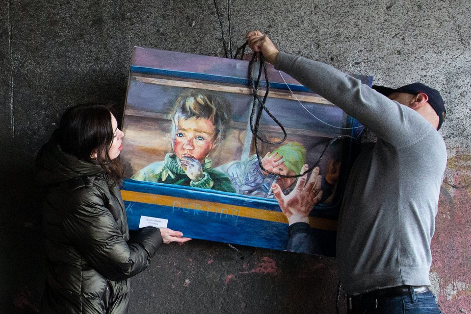 Zum Jahrestag der Befreiung von der russischen Besatzung hängen eine ukrainische Frau und ein Mann ein Kunstgemälde auf zu einer Ausstellung in Kiew
